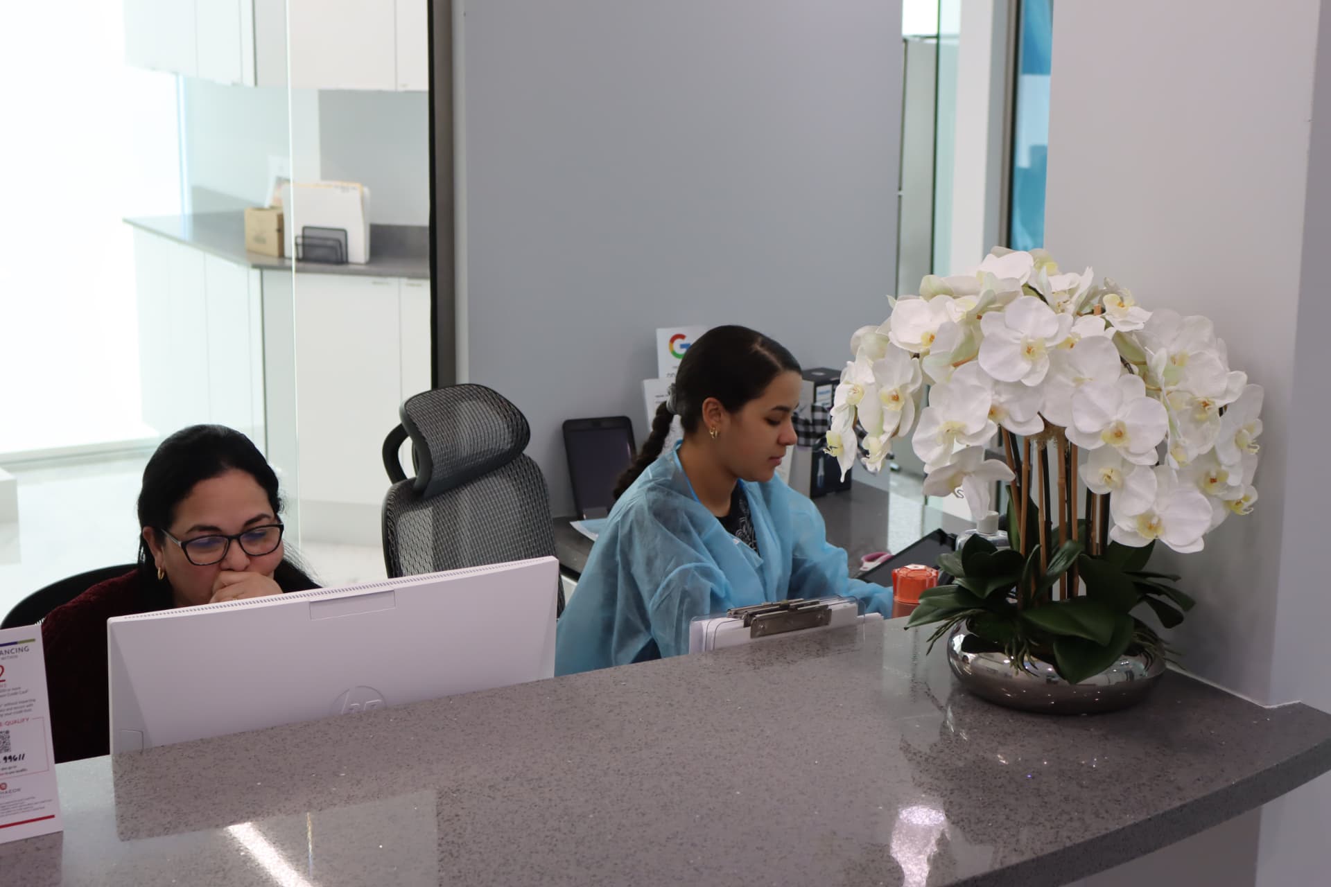 Beacon Dental front desk team beside white orchids in the reception area